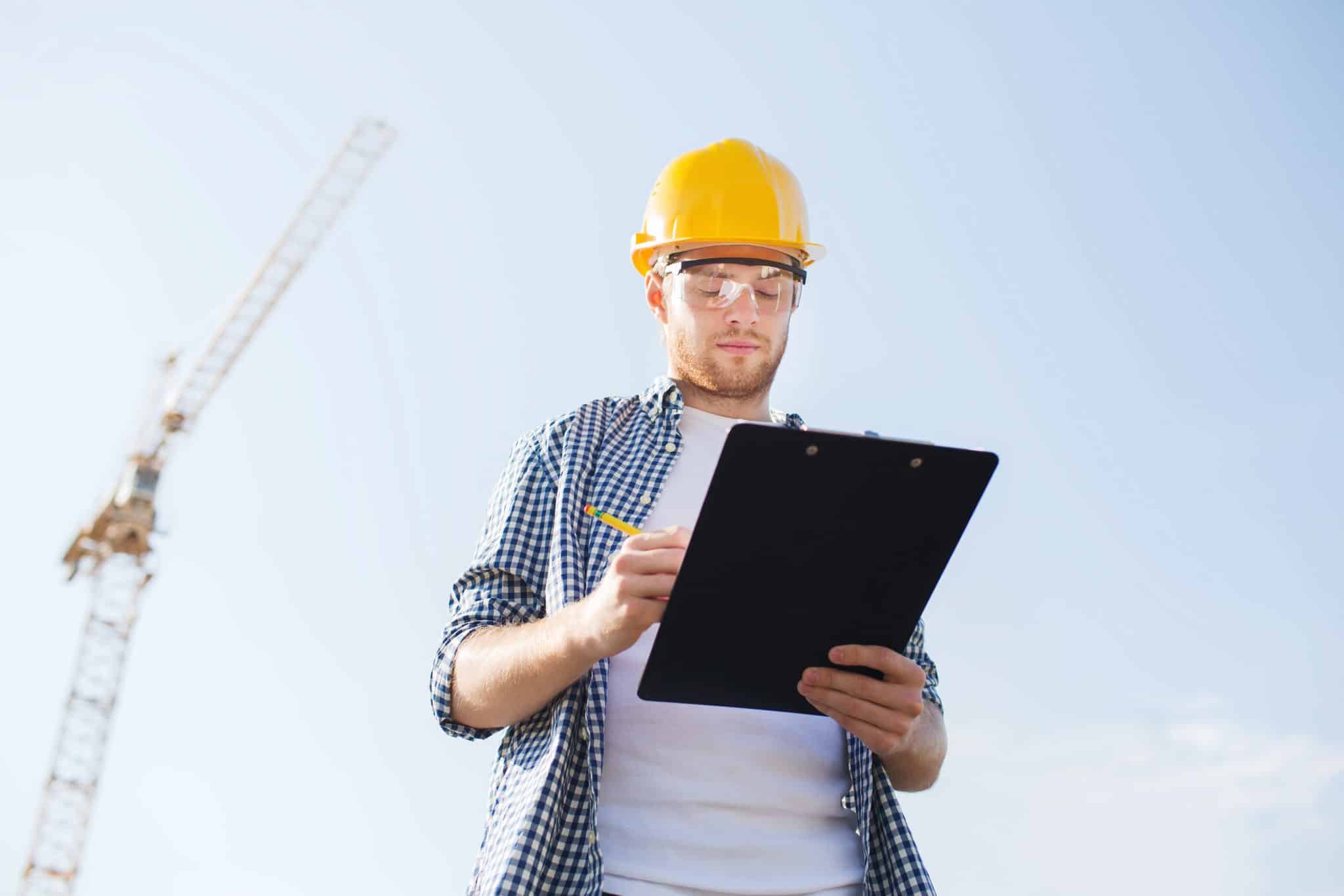 builder in hardhat with clipboard outdoors